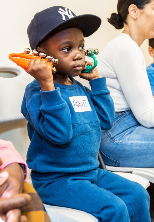 A DMF participant wearing a New York Yankees hat shakes instruments with jingle bells