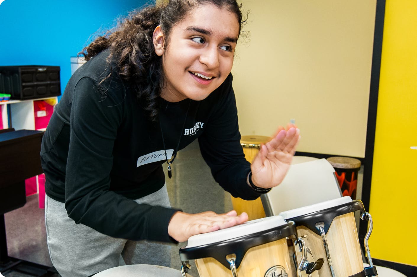 A DMF participant looks up and smiles while playing drums with their hands