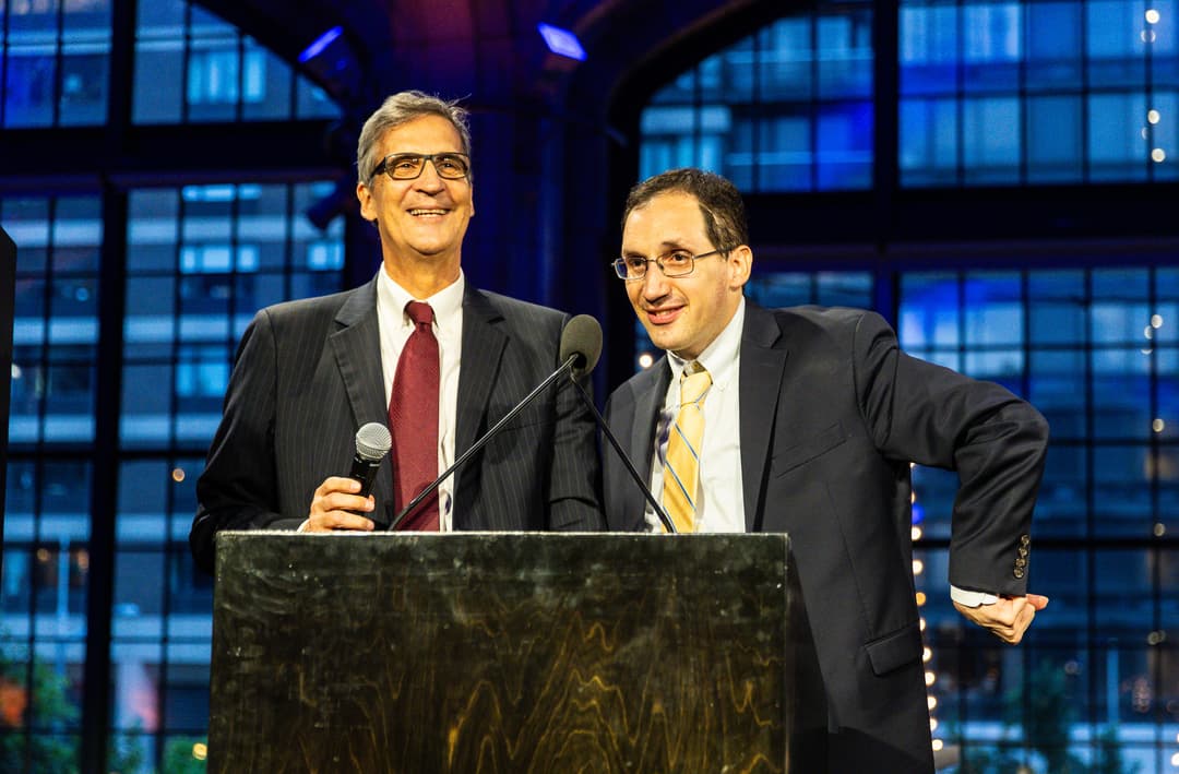 Daniel and Ken Trush speaking at a podium at the 2024 Benefit
