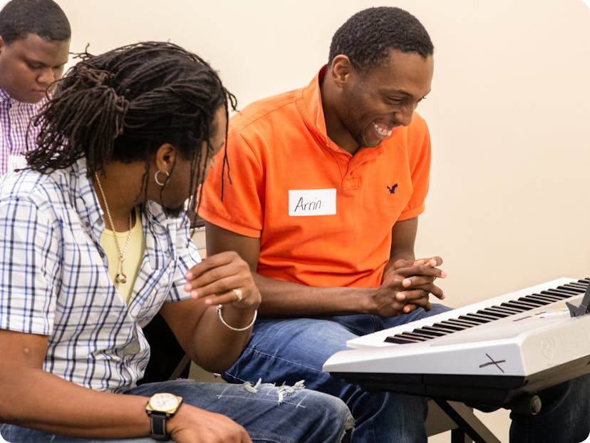 2 DMF participants share a laugh as one of them plays the keyboard