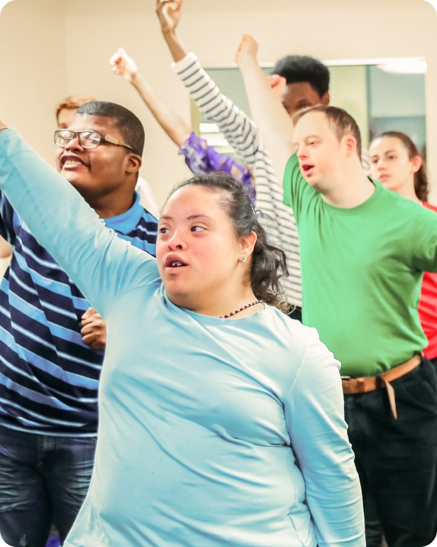 A group of DMF participants raise their right arms