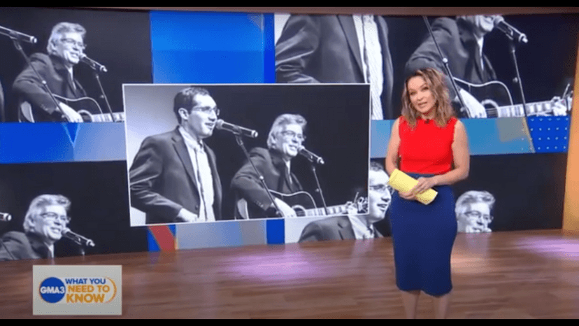 Photo of a woman standing in front of a screen showing some images of Daniel Trush and Gerry Powers