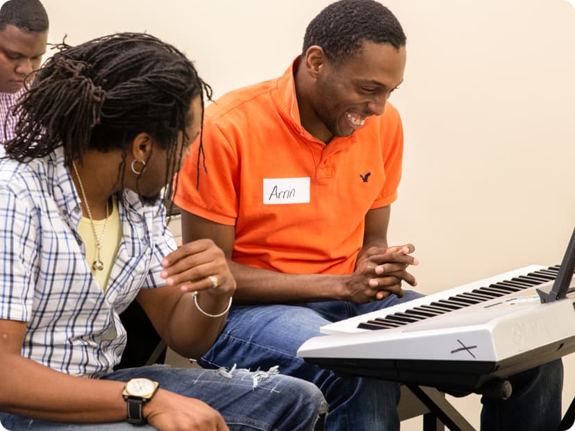 2 DMF participants share a laugh as one of them plays the keyboard