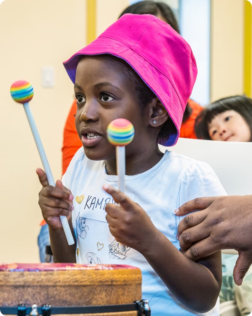 A DMF participant holding colorful drum sticks looks up