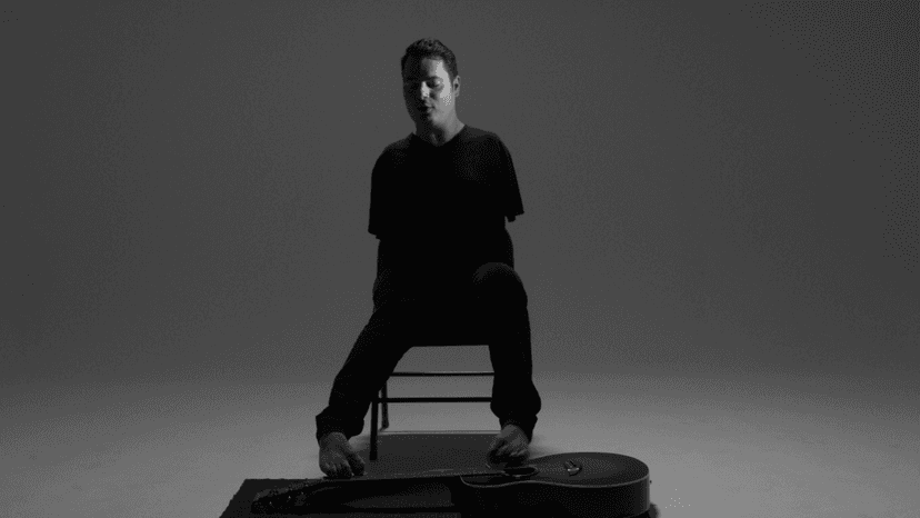 Thumbnail for George Dennehy's video "Your Moment". It shows the artist sitting in a chair, with a guitar at his feet. He is a young light skinned man with straight brown hair. He does not have arms.