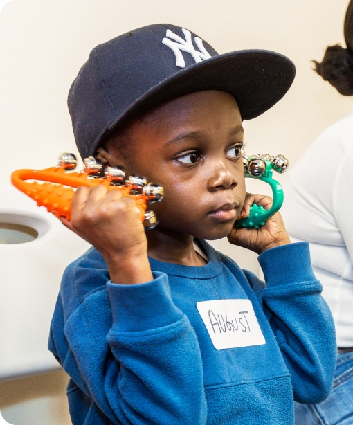 A DMF participant wearing a New York Yankees hat shakes instruments with jingle bells