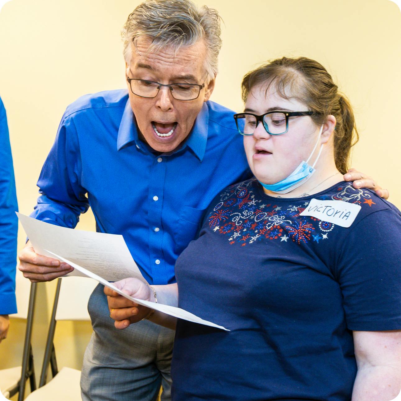 DMF Artistic Director Gerry sings with a DMF participant while reading lyrics off of a piece of paper
