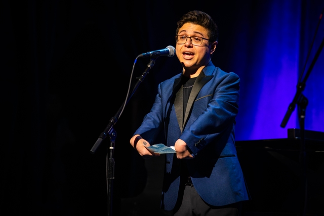 Performer speaking into a microphone with limb differences