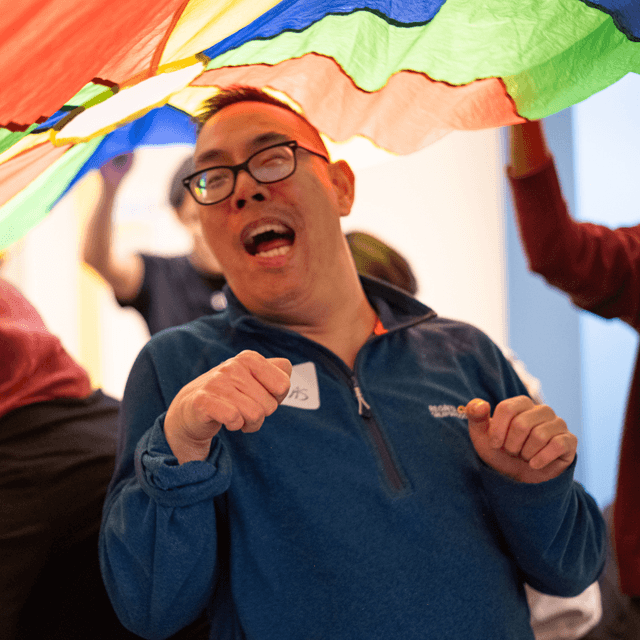 Member smiling under parachute in classroom